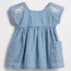 Baby-jeetje met geborduurde denimzakken in de jurk