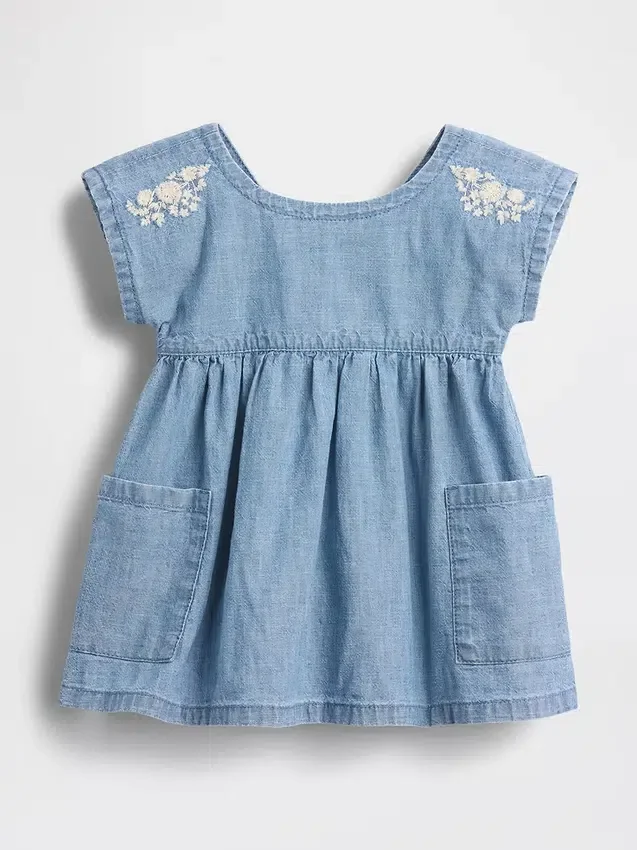 Baby-jeetje met geborduurde denimzakken in de jurk