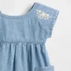Baby-jeetje met geborduurde denimzakken in de jurk