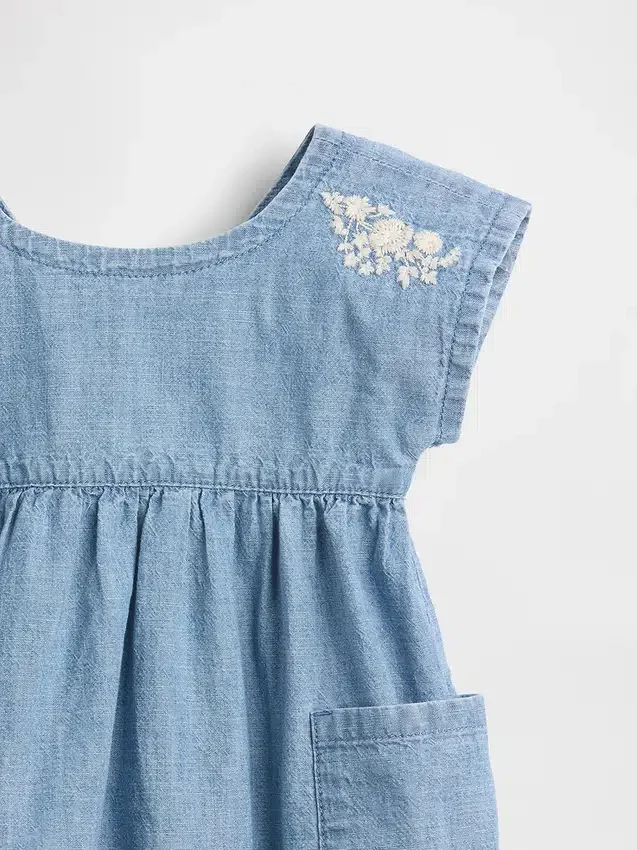 Baby-jeetje met geborduurde denimzakken in de jurk